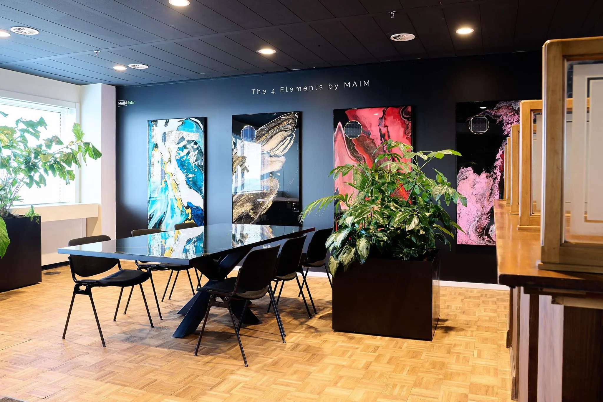 Moderne vergaderruimte aan de Johan Huizingalaan met kunst aan de muur, glazen tafel, zwarte stoelen en grote kamerplanten.